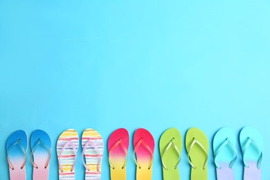 Photo of Different flip flops and space for text on blue background, flat lay. Summer beach accessories