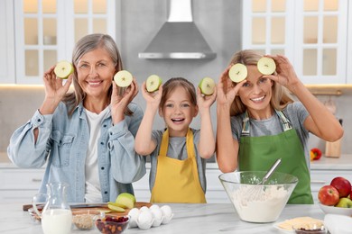 Photo of Three generations. Happy grandmother, her daughter and granddaughter having fun while cooking together in kitchen