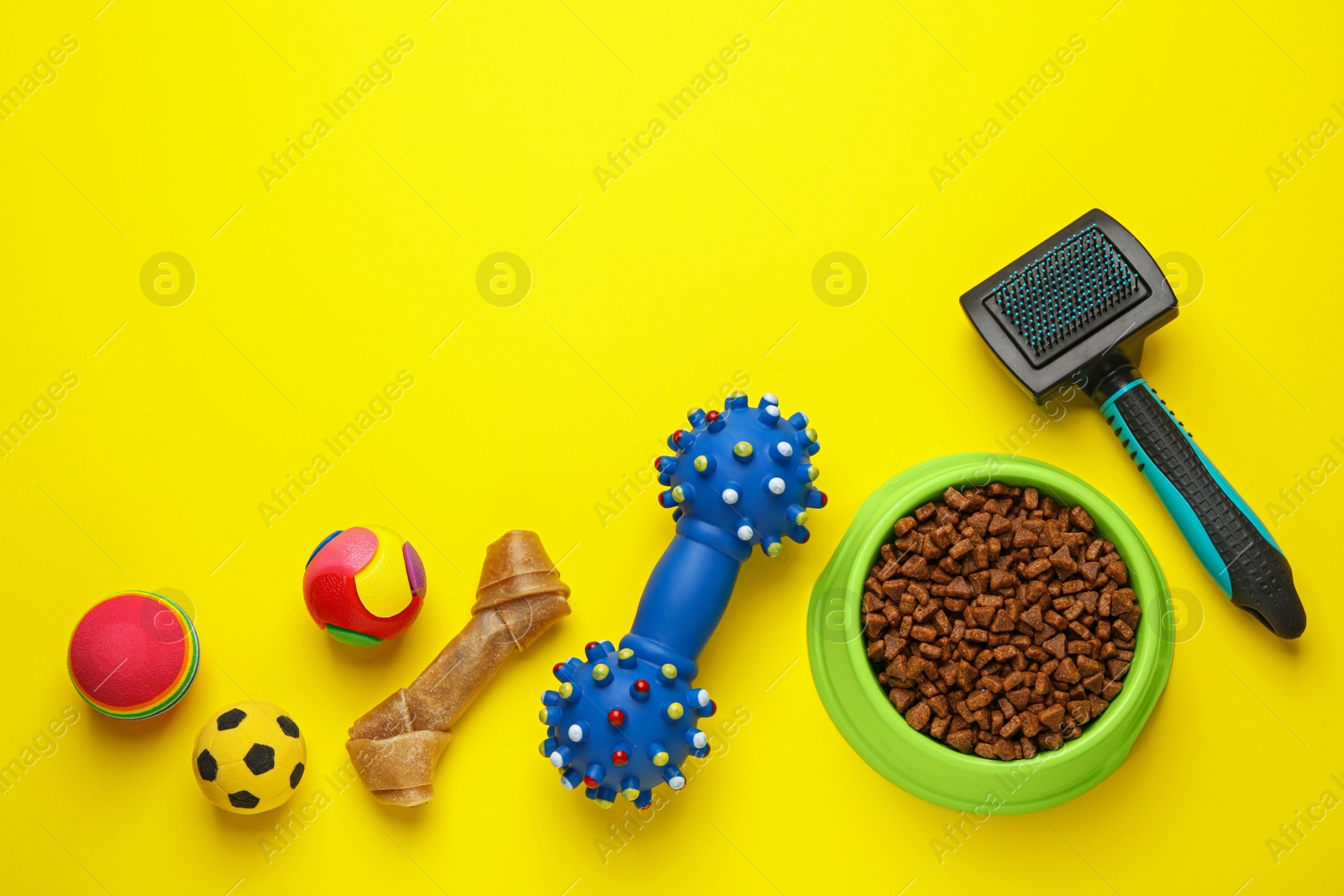 Photo of Flat lay composition with pet toys and feeding bowl on yellow background, space for text