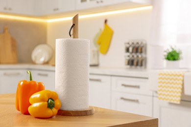 Roll of white paper towels and bell peppers on wooden table in kitchen, space for text
