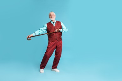 Photo of Cheerful senior man with walking cane on light blue background