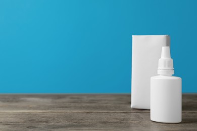 Nasal spray and package on wooden table against light blue background. Space for text