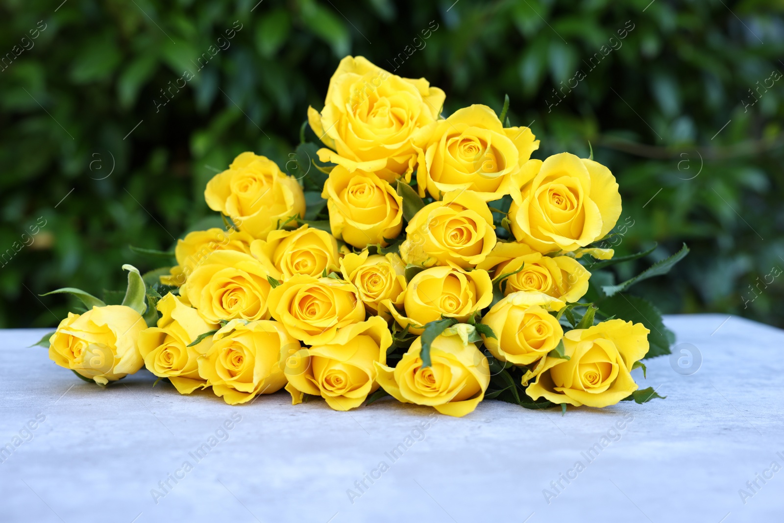 Photo of Beautiful bouquet of yellow roses on light table outdoors