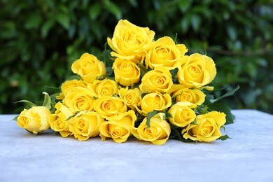 Beautiful bouquet of yellow roses on light table outdoors