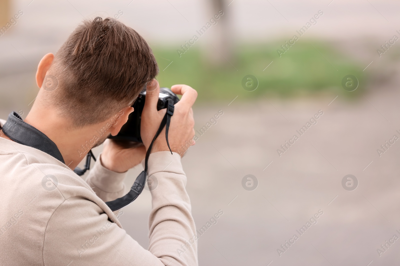 Photo of Male photographer with professional camera on blurred background. Space for text