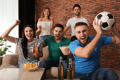 Group of friends watching football at home