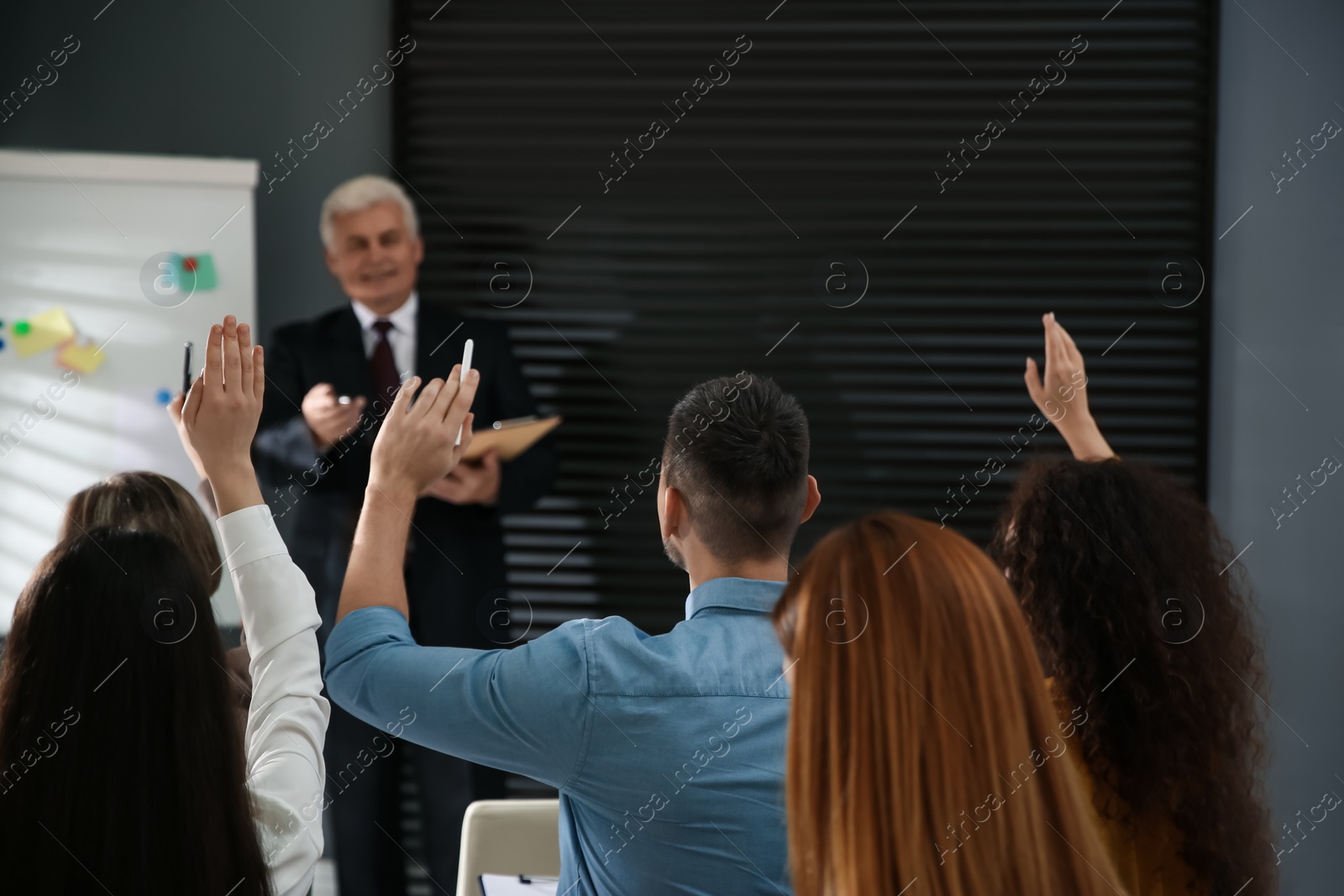 Photo of People raising hands to ask questions at seminar in office