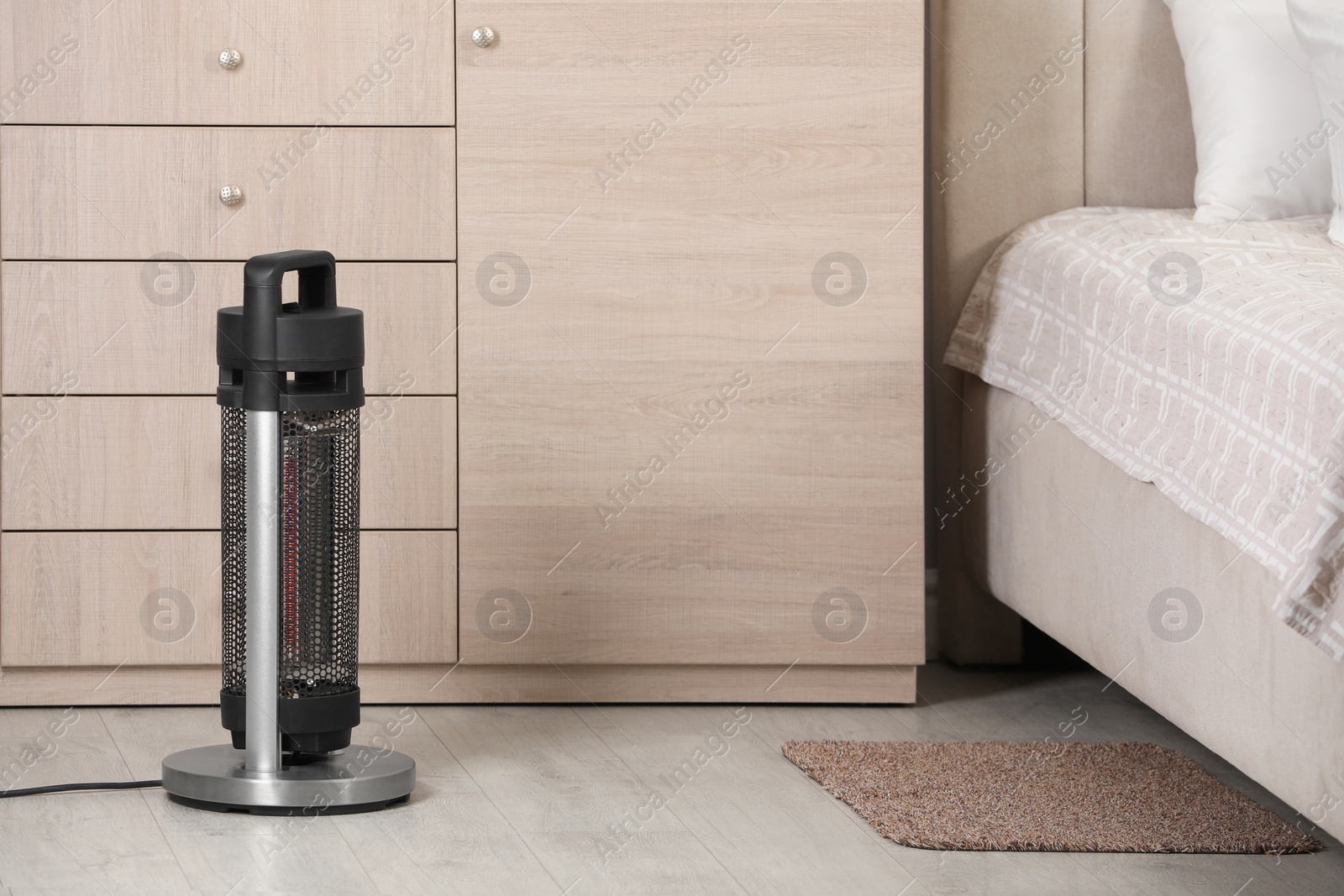 Photo of Modern infrared heater on floor in bedroom