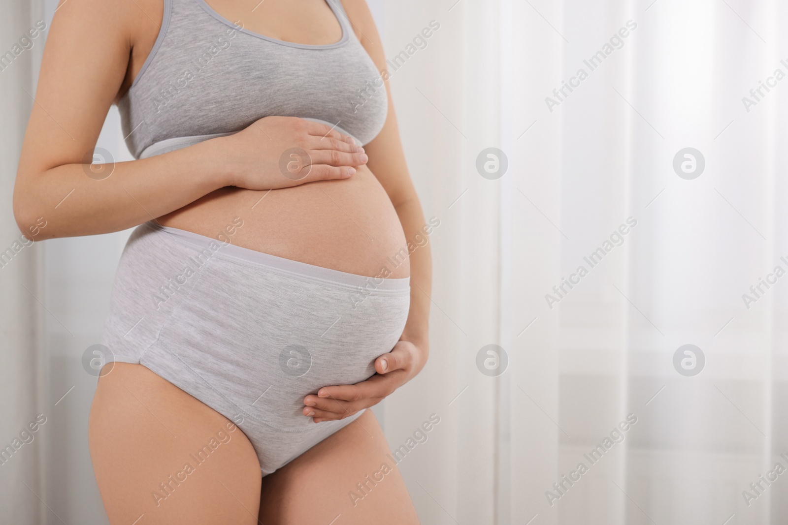 Photo of Pregnant woman in comfortable maternity underwear indoors, closeup. Space for text