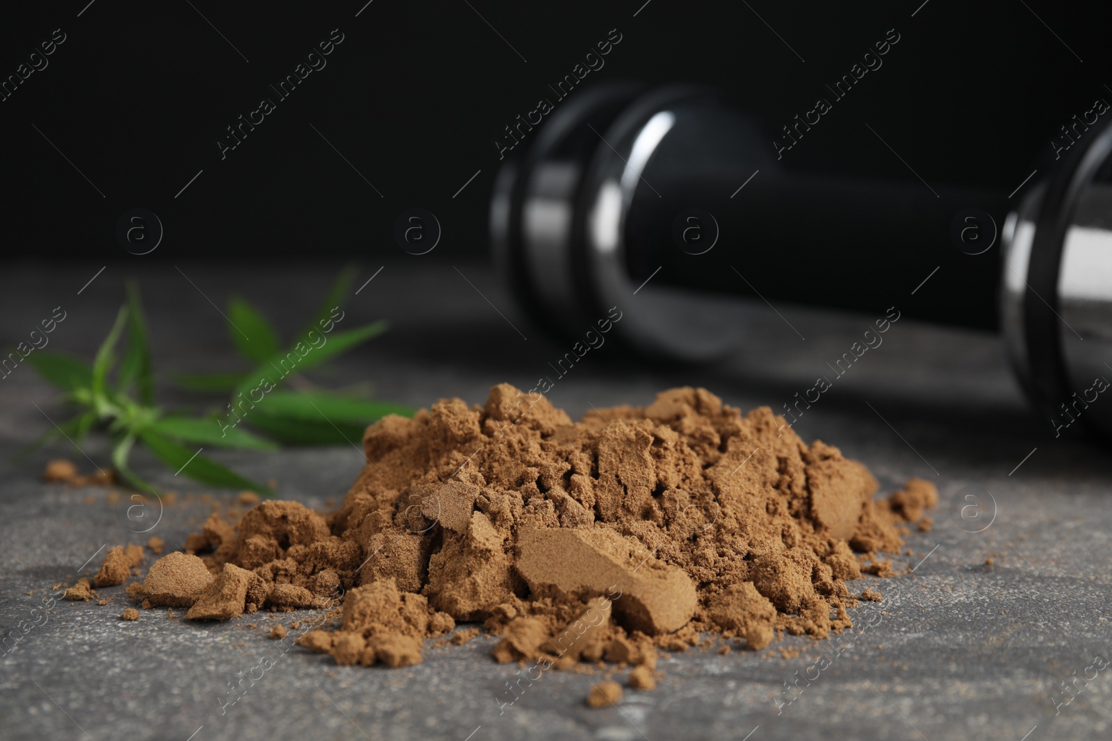 Photo of Hemp protein powder and dumbbell on grey table