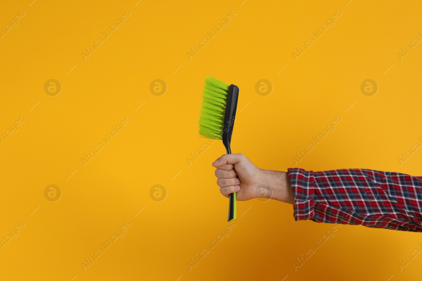 Photo of Young man with broom on orange background, closeup. Space for text