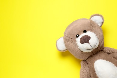 Photo of Cute teddy bear on yellow background, top view. Space for text