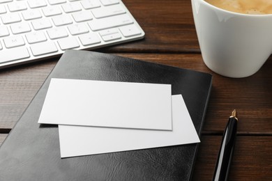 Photo of Blank business cards, notebook and pen on wooden table, closeup. Mockup for design