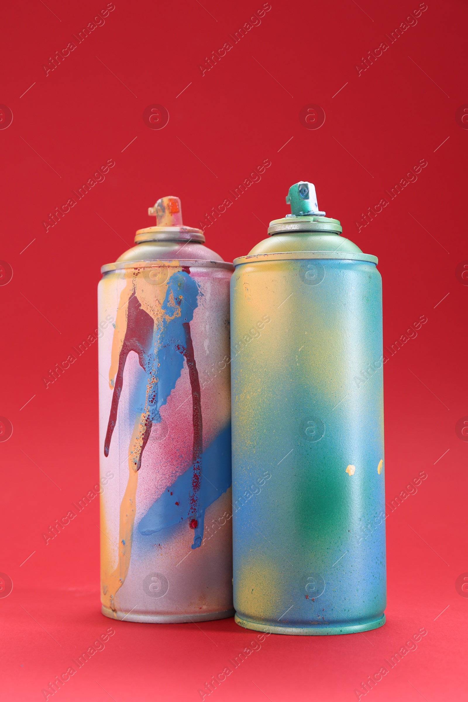 Photo of Two spray paint cans on red background