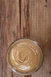 Photo of Tasty nut paste in jar on wooden table, top view. Space for text