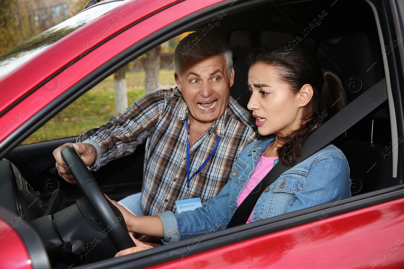 Photo of Young woman and senior instructor in car. Fail driving license exam