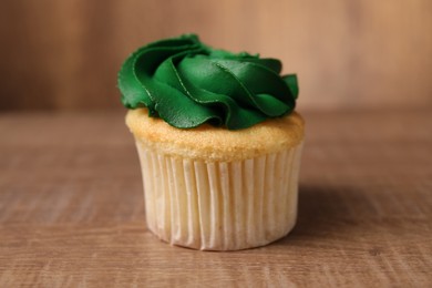 Delicious cupcake with bright cream on wooden table, closeup