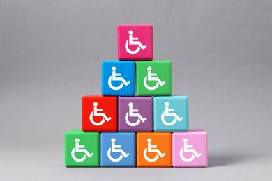 Image of Inclusion concept. Pyramid of colorful cubes with international symbols of access on grey background