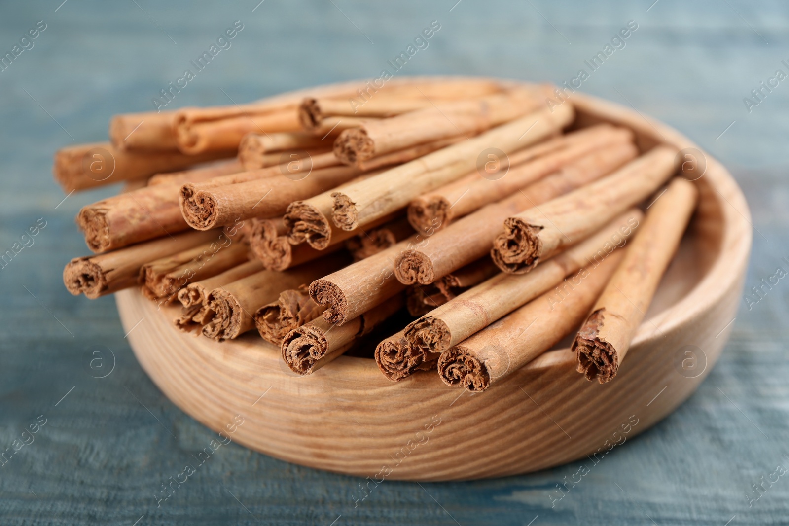 Photo of Aromatic cinnamon sticks on blue wooden table, closeup