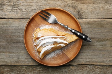 Piece of tasty homemade quince pie with powdered sugar and fork on wooden table, top view