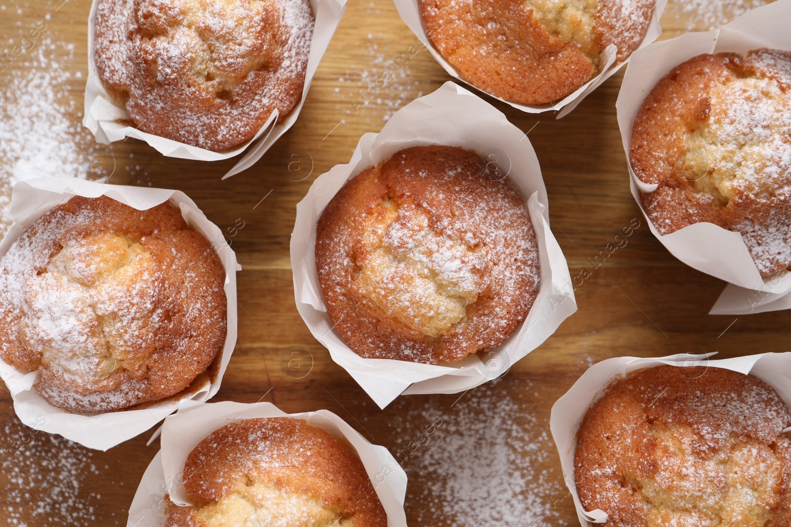 Photo of Delicious muffins on wooden board, top view