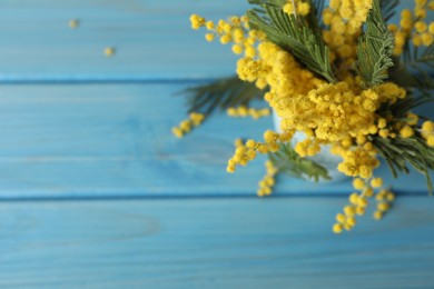 Beautiful mimosa flowers on light blue wooden table, top view. Space for text