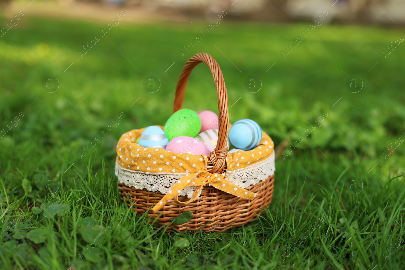 Photo of Easter celebration. Painted eggs in wicker basket on green grass