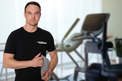 Image of Portrait of professional personal trainer with clipboard in gym. Space for text