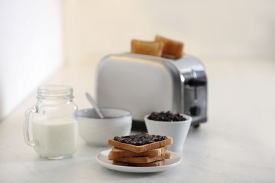 Modern toaster and delicious breakfast on table in kitchen