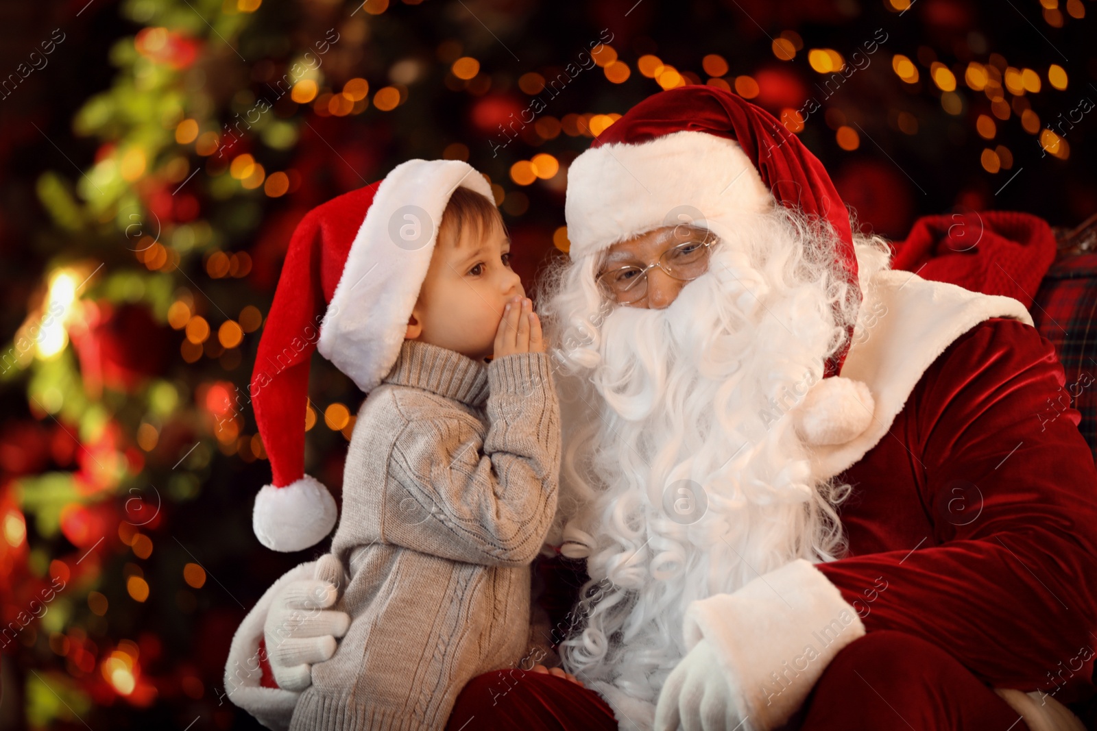 Photo of Santa Claus and little boy near Christmas tree indoors