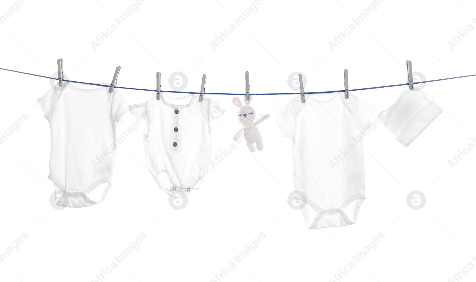 Photo of Different baby clothes and toy drying on laundry line against white background