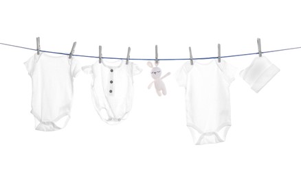 Photo of Different baby clothes and toy drying on laundry line against white background