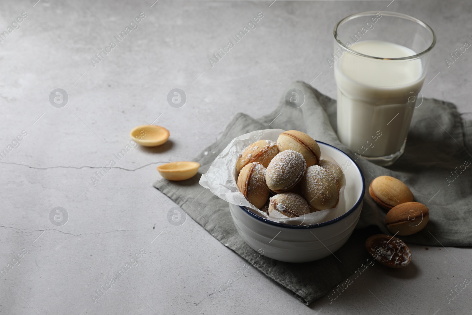 Photo of Delicious walnut shaped cookies with filling and milk on grey table. Space for text