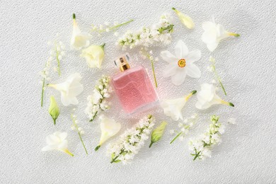 Luxury perfume and floral decor on white plastic surface, flat lay