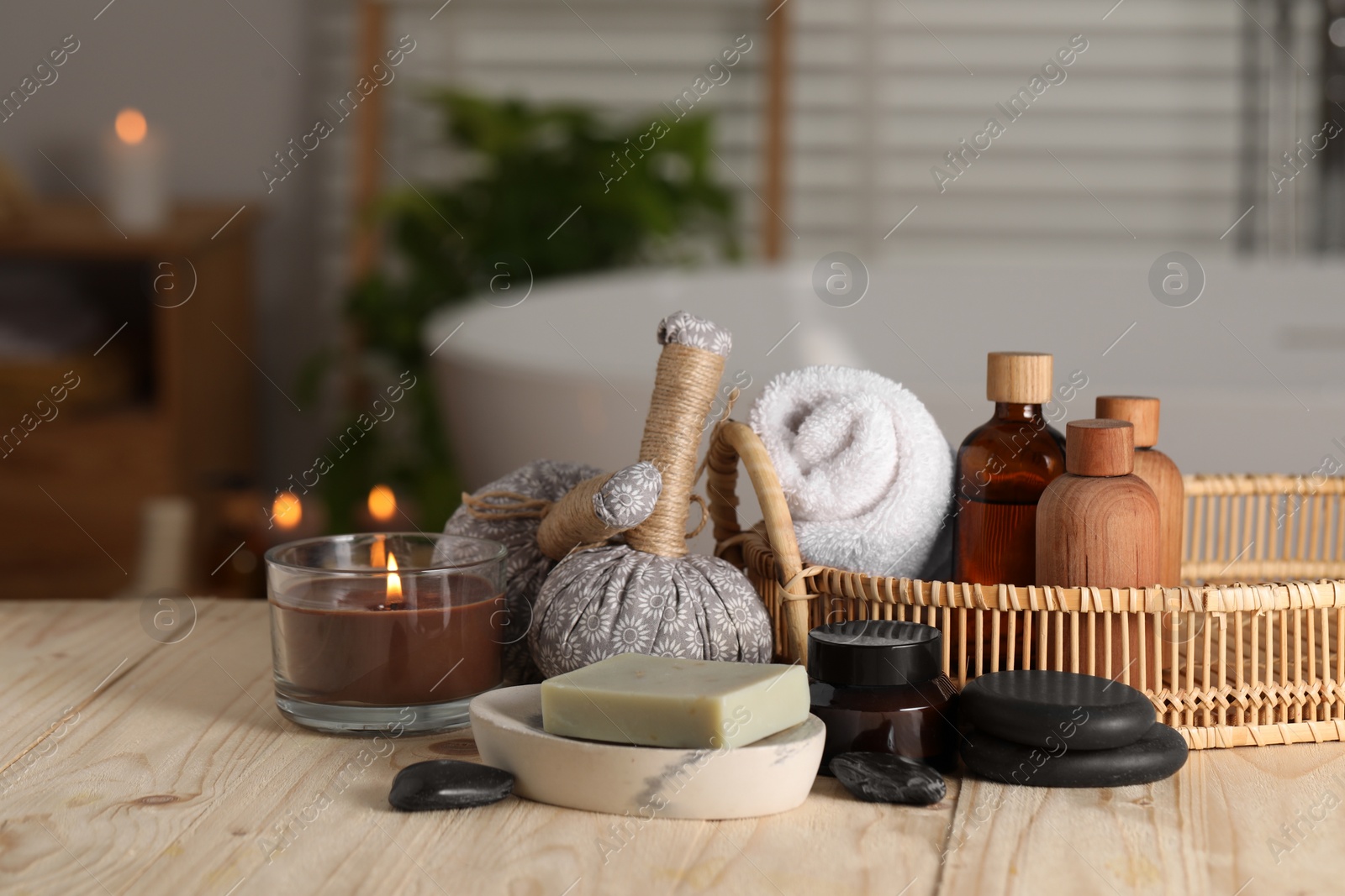 Photo of Composition with spa products and burning candle on wooden table in bathroom