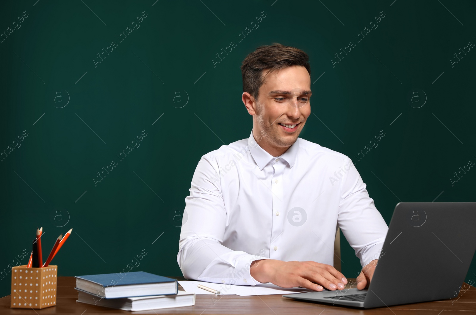 Photo of Portrait of male teacher working at table against color background