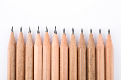 Many sharp graphite pencils on white background, top view