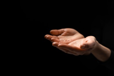 Photo of Religion. Woman with open palms praying on black background, closeup. Space for text