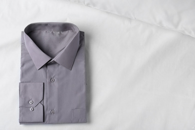 Stylish grey shirt on white fabric, top view with space for text. Dry-cleaning service