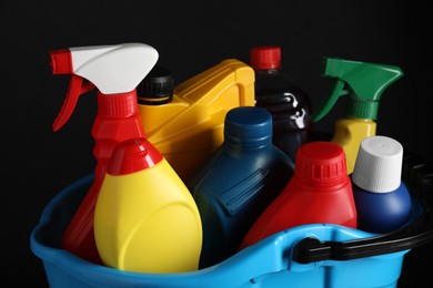 Photo of Light blue bucket with car cleaning products on black background, closeup