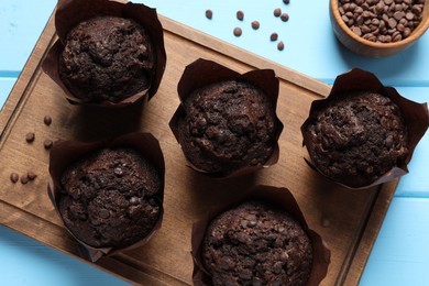 Photo of Tasty chocolate muffins on light blue wooden table, top view