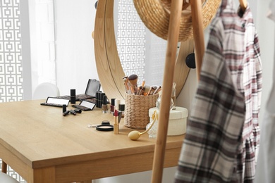 Photo of Cosmetics and brushes on dressing table in makeup room