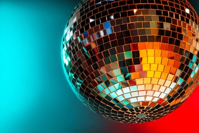 Photo of Shiny disco ball under color lights, closeup. Space for text