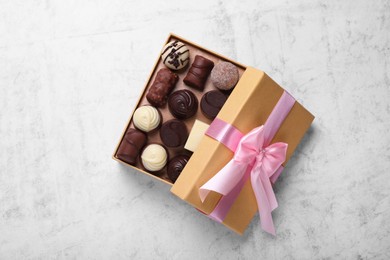 Photo of Open box with delicious chocolate candies on white table, top view