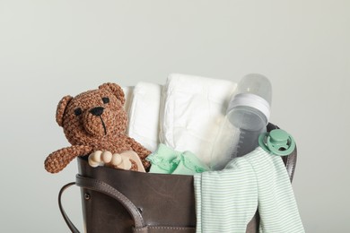 Photo of Mother's bag with baby's stuff on light grey background