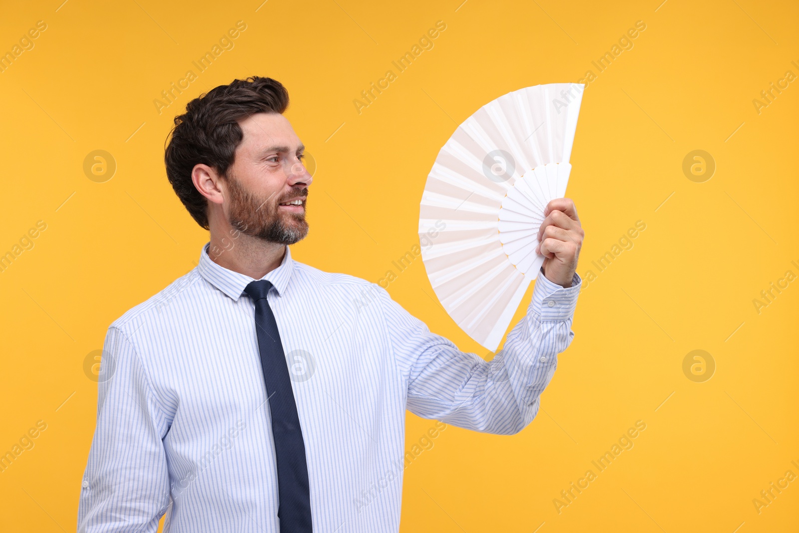 Photo of Happy man holding hand fan on orange background