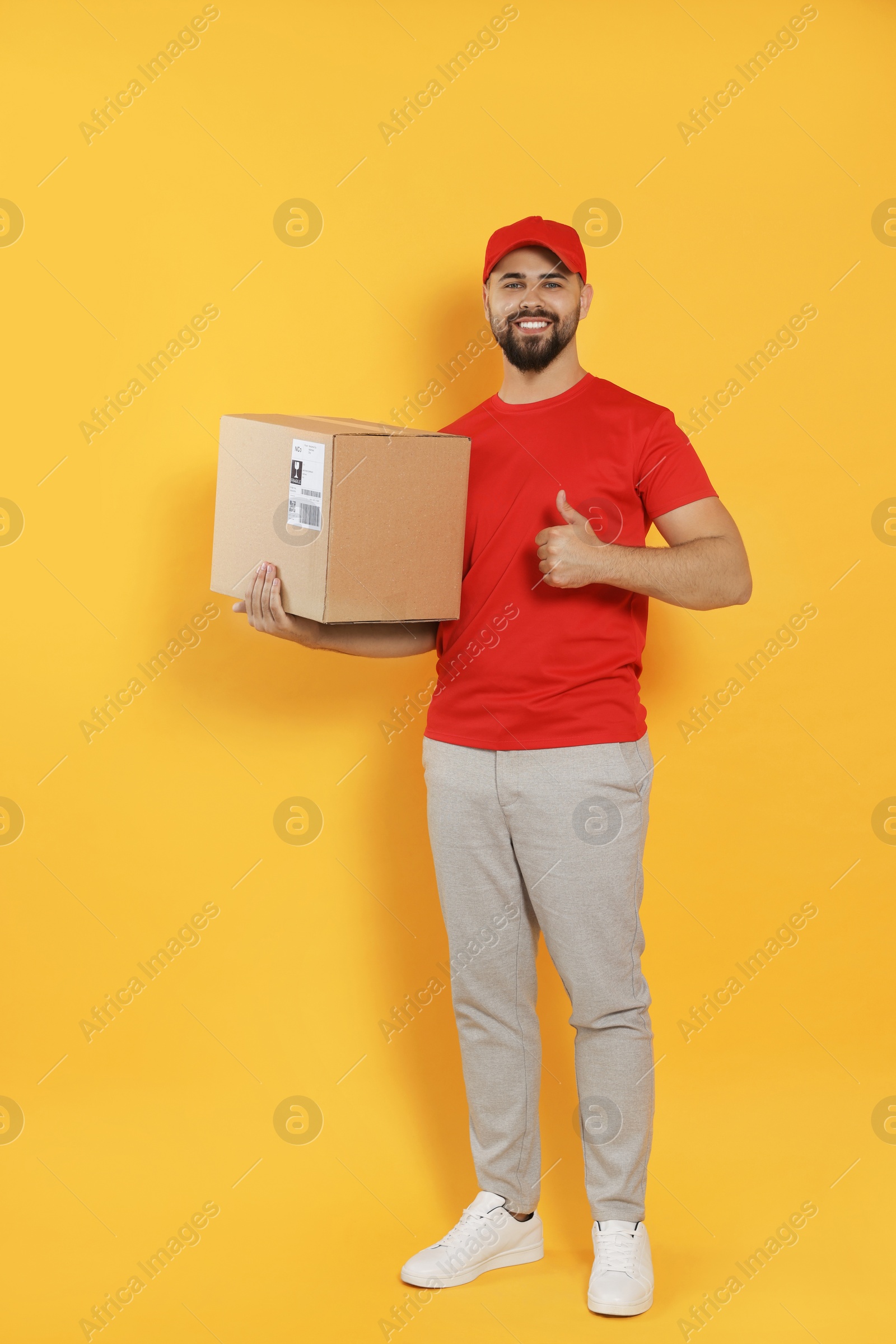 Photo of Courier holding cardboard box on yellow background