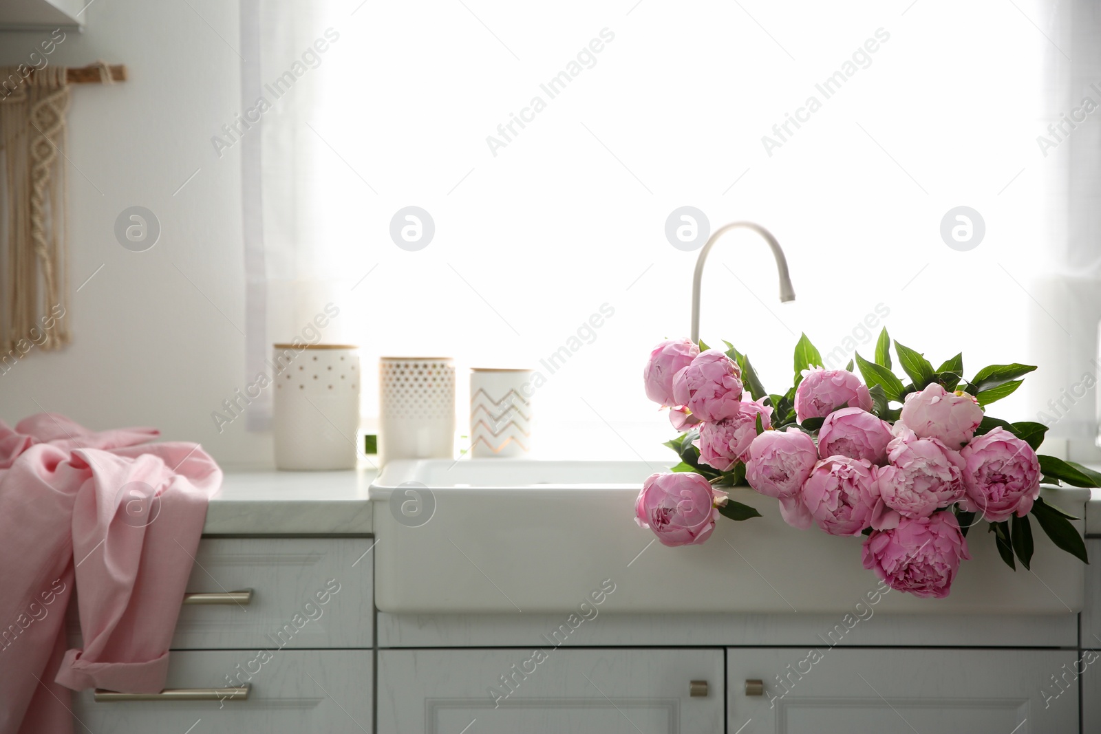 Photo of Bouquet of beautiful pink peonies in kitchen sink