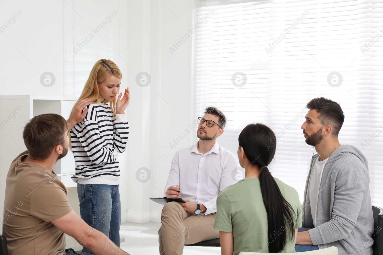 Photo of Psychotherapist working with group of drug addicted people at therapy session indoors