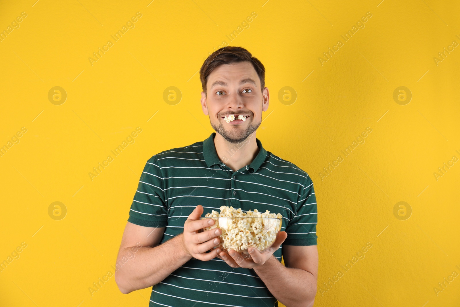 Photo of Man eating tasty popcorn on color background